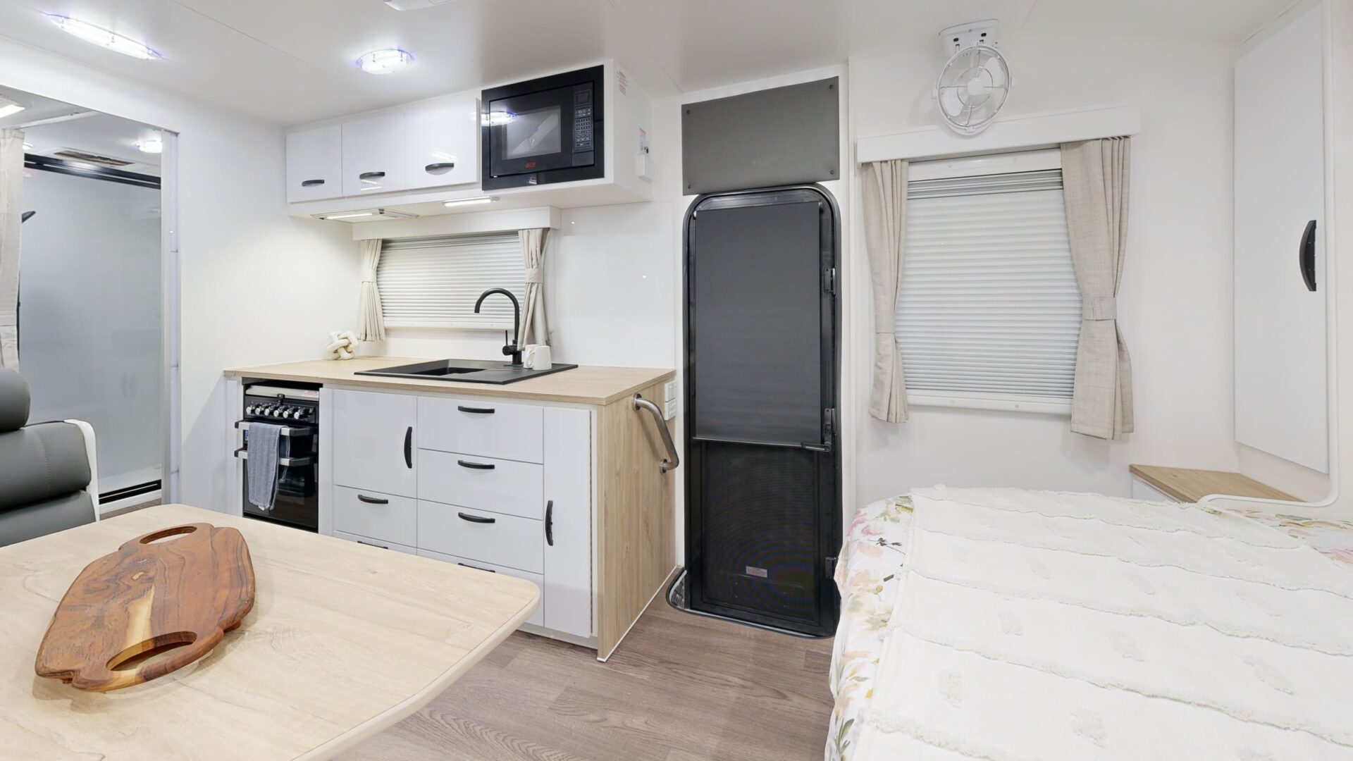 Leader Xpedition caravan interior — island queen bedroom with padded headboard, reading lights, timber overhead cabinetry and skylight hatch