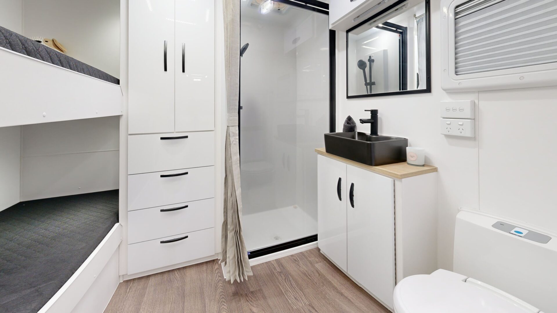 Leader Xpedition caravan interior ensuite — separate shower cubicle, black vessel basin on timber vanity, toilet and full-height storage