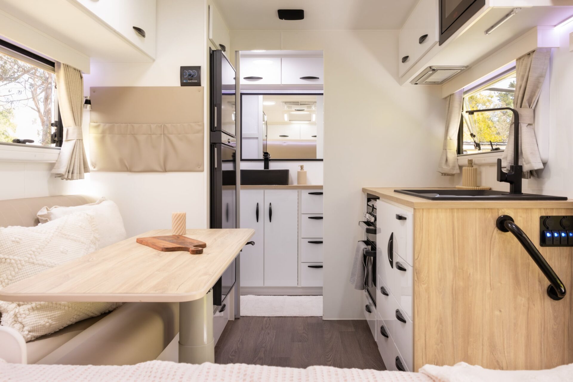Supreme Territory interior — dinette and kitchen with timber-look benchtops, microwave, switch panel and ensuite at rear